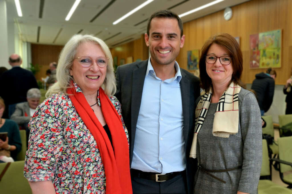 Un homme et deux femmes sourient à l'objectif